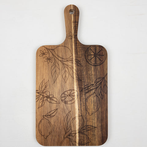 Acacia wood cutting board decorated with a detailed laser-engraved citrus and leaf pattern, crafted for kitchen presentation or chopping tasks.