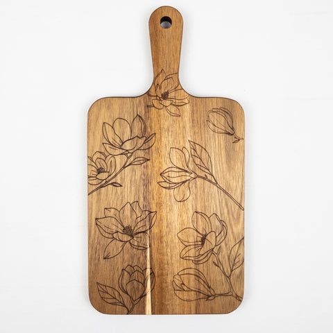 Acacia wood cutting board with a floral laser-engraved design of delicate blooming flowers and leaves, serving both decorative and functional purposes.