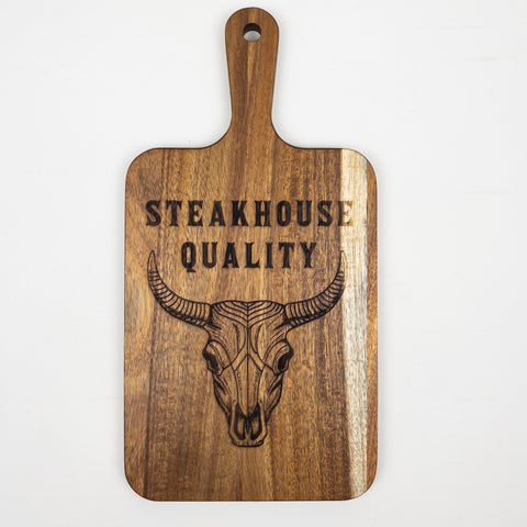 VIVERA acacia paddle cutting board laser engraved longhorn skull with text “Steakhouse Quality,” rustic meat serving board